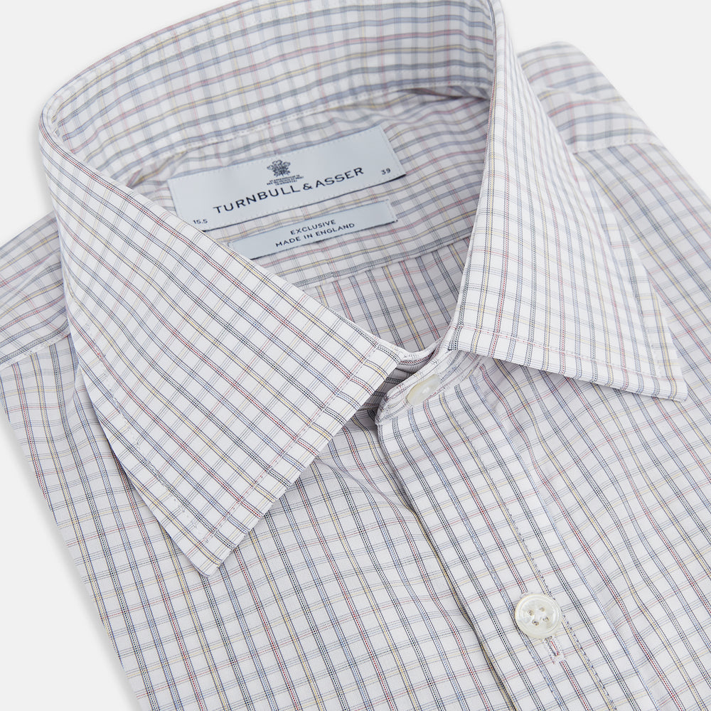 The Turnbull & Asser Sky Blue Multi Graph Check Shirt features long sleeves, a button-up front, pointed T&A collar, buttoned cuffs, and a small blue-and-white check pattern, shown on a white background.