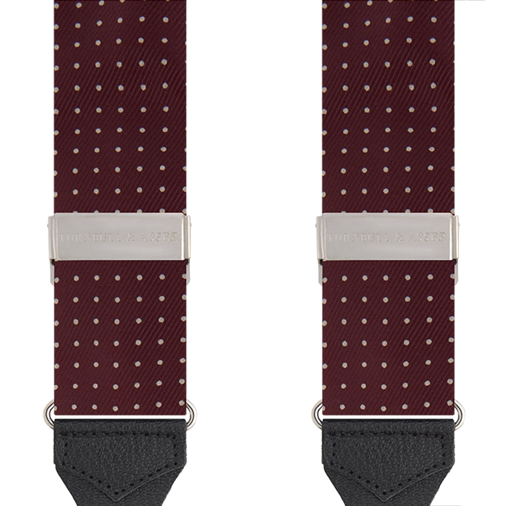 Turnbull & Asser Burgundy Small Spot Adjustable Silk Braces, featuring small white dots, black leather ends, and silver clasps, are displayed vertically on a plain white background for refined sartorial style.