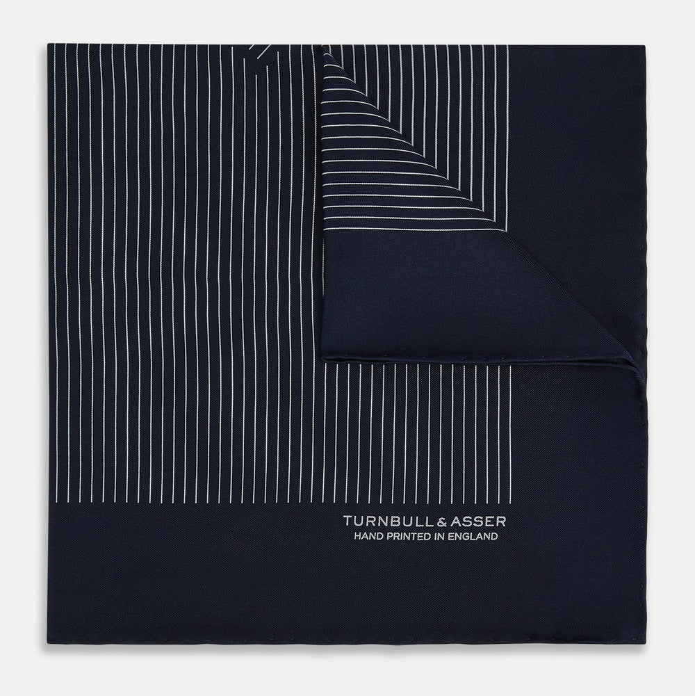 A Navy and Grey Stripe Silk Pocket Square by Turnbull & Asser, featuring hand-rolled edges and brand text in the corner. One corner is folded to show the reverse side.