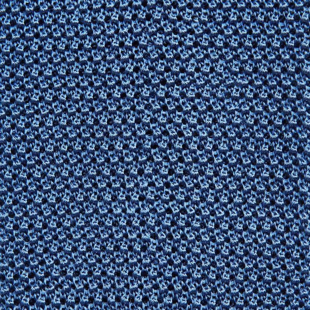 The Turnbull & Asser Knitted Mid Blue Silk Plain Tie features a textured knit and is shown rolled up on a plain white background—a refined accessory that pairs perfectly with formal shirts.