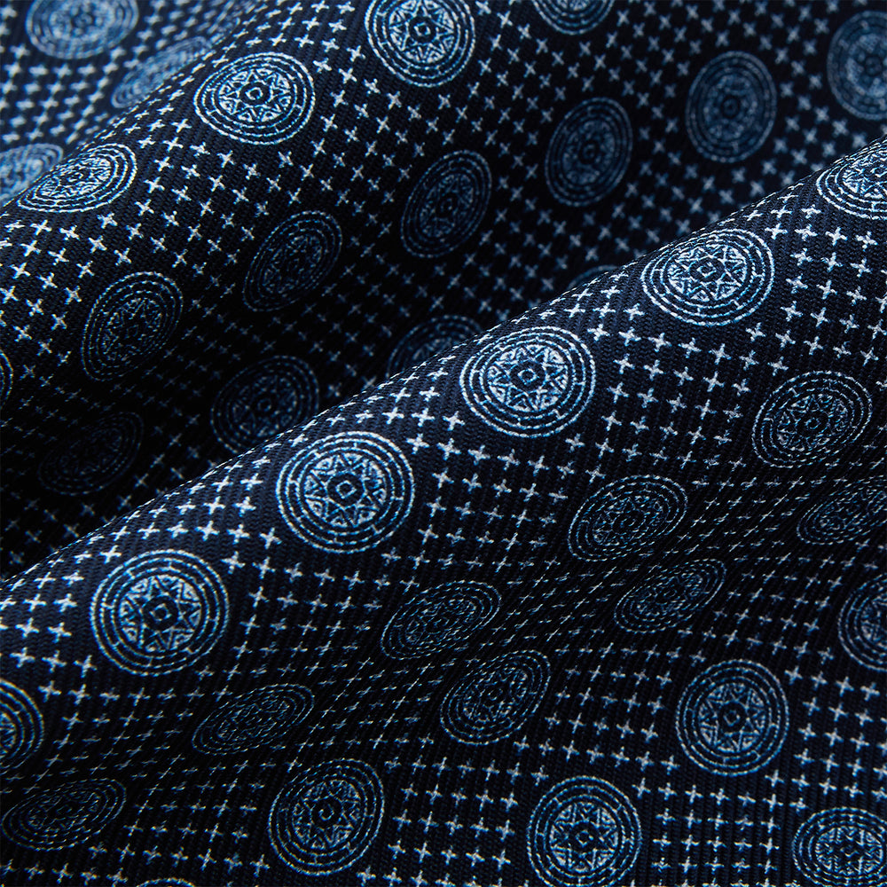The Turnbull & Asser Navy Medallion Silk Cravat features a white geometric and circular pattern, its classic design and rich navy hue echoing refined British elegance.