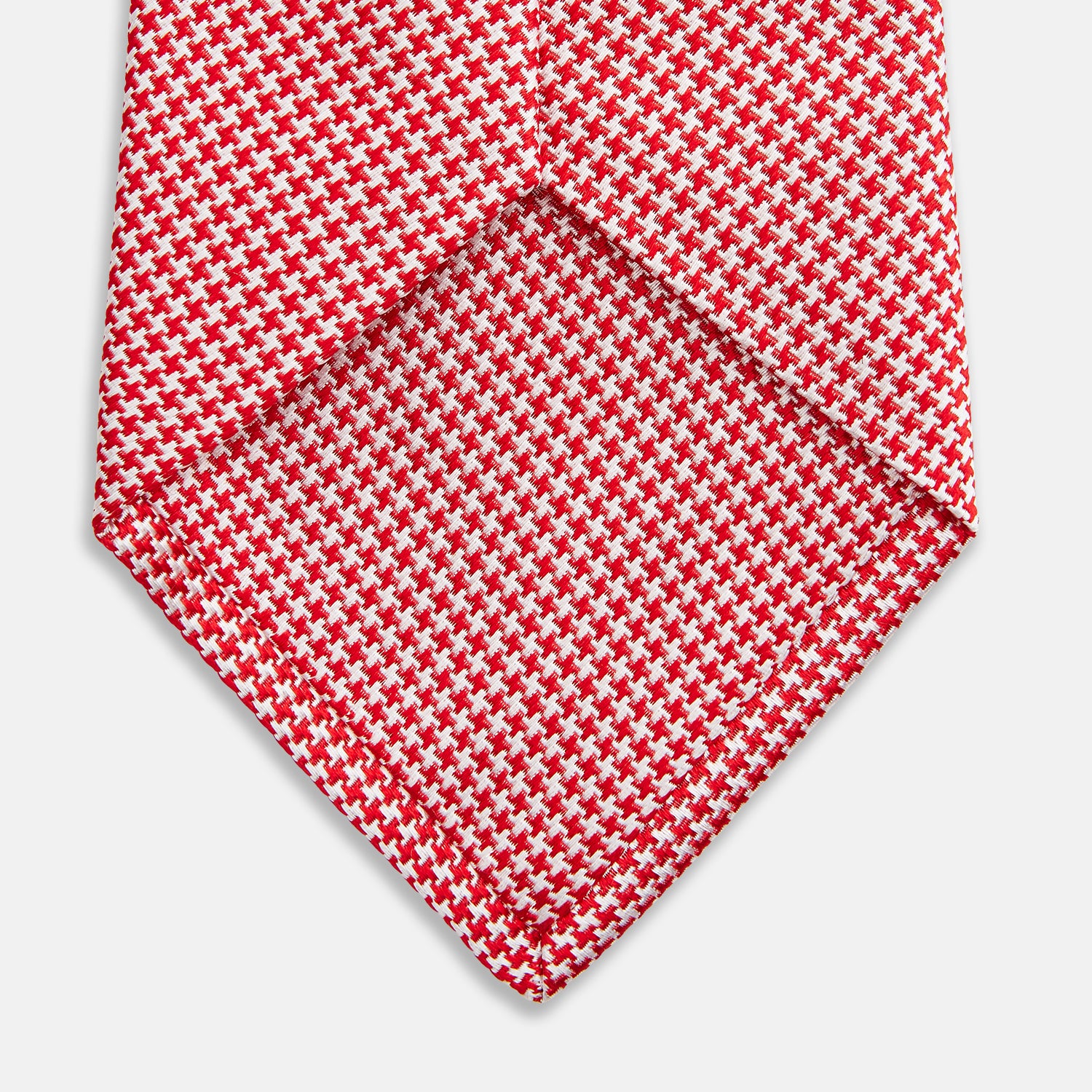 View 4 of product The Turnbull & Asser Red and White patterned silk tie, crafted from fine silk with a small geometric design, is elegantly rolled and displayed on a white background—a refined men’s accessory.