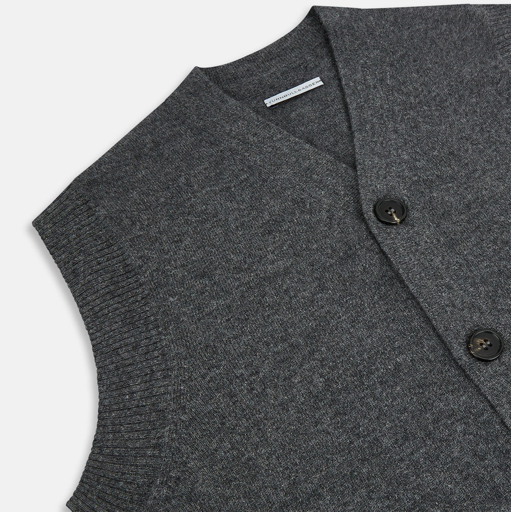 The Turnbull & Asser Charcoal Grey Cashmere Sleeveless Cardigan is a men's knit V-neck vest with ribbed collar, hem, and two front pockets, shown in dark grey melange against a white background.