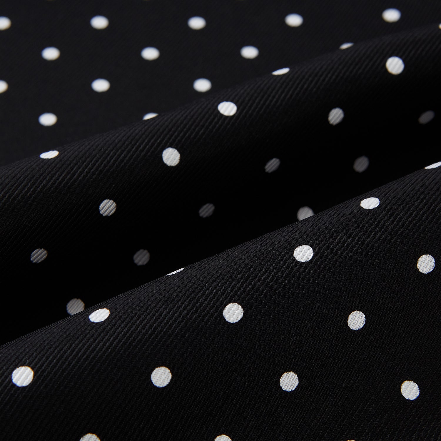 View 3 of product The Turnbull & Asser Black and White Spotted Silk Scarf with Fringes features a classic polka dot design, silver fringe edges, and the brand name printed near each end.