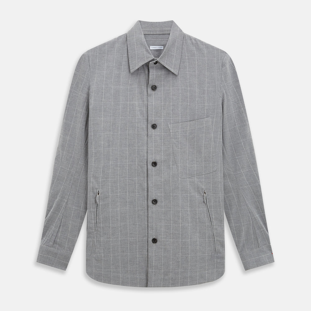 The Turnbull & Asser Grey Check Hampstead Overshirt features a light gray check pattern, pointed collar, chest pocket, and two zippered side pockets, displayed flat against a white background.