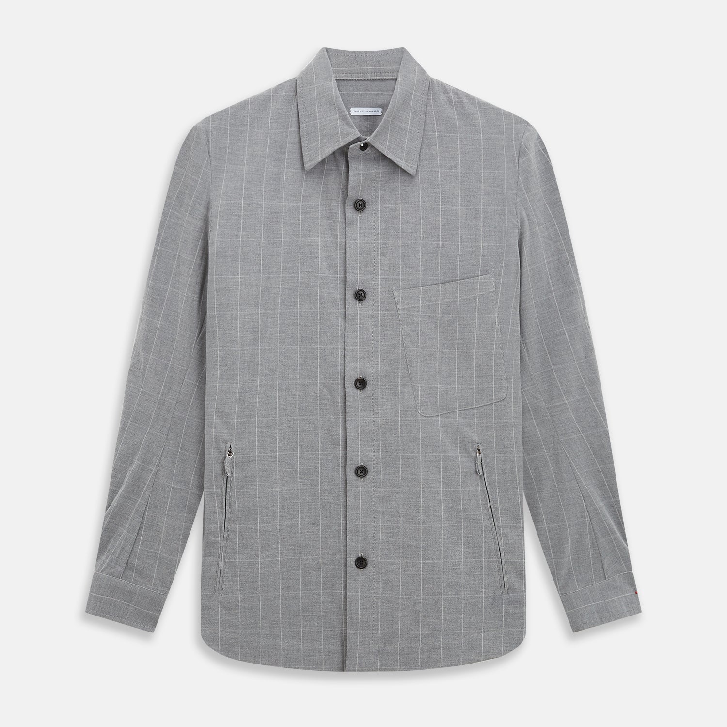 View 1 of product The Turnbull & Asser Grey Check Hampstead Overshirt features a light gray check pattern, pointed collar, chest pocket, and two zippered side pockets, displayed flat against a white background.