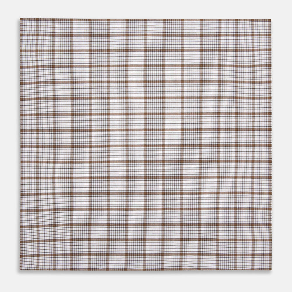 The Turnbull & Asser Hand Rolled Brown Overlay Check Handkerchief is a rectangular white cotton accessory with evenly spaced brown and black grid lines, forming squares—a timeless classic for gentlemen.