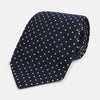 View 1 of product The Silver and Navy Micro Dot Silk Tie by Turnbull & Asser features a refined micro dot pattern, perfect for adding a classic accent to formal attire. Shown neatly rolled on a white background.