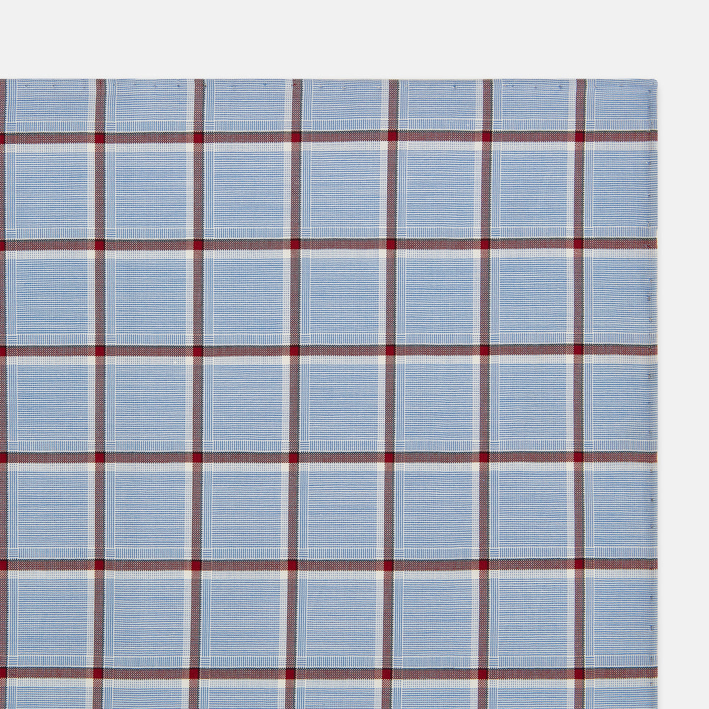 The Turnbull & Asser Blue and Burgundy Windowpane Check Hand-Rolled Handkerchief features a light blue fabric with white, red, and dark blue stripes forming a classic plaid grid.
