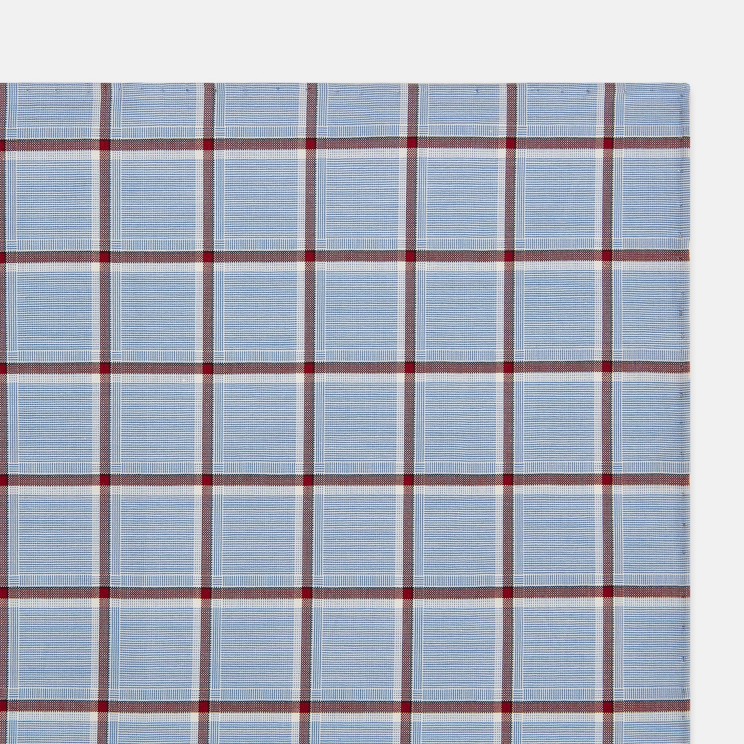 View 3 of product The Turnbull & Asser Blue and Burgundy Windowpane Check Hand-Rolled Handkerchief features a light blue fabric with white, red, and dark blue stripes forming a classic plaid grid.
