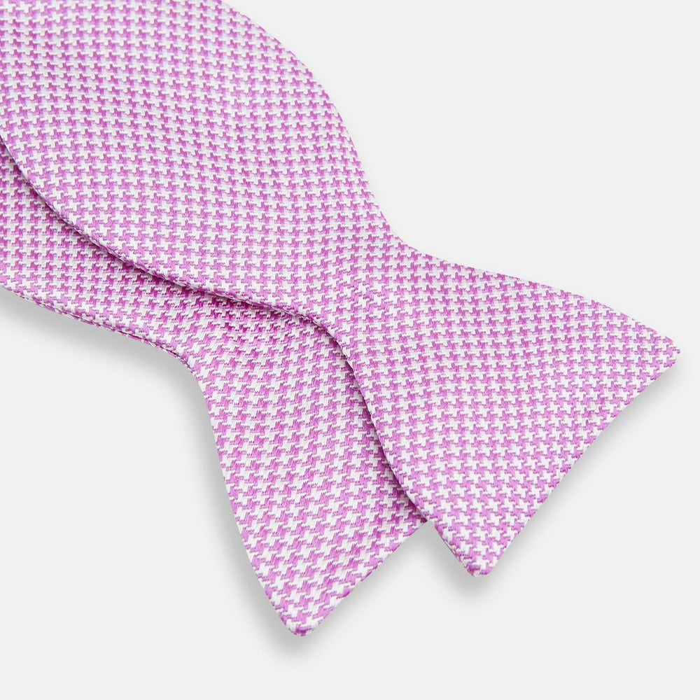 The Turnbull & Asser Pink and White Houndstooth Silk Bow Tie is shown against a plain white background, making it a stylish choice for formalwear.