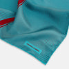 View 2 of product The Turnbull & Asser Turquoise and Red Stripe Silk Pocket Square features thin navy stripes with a bold vertical red stripe, partially folded to reveal the reverse pattern and the brand's logo, showcasing its British heritage.