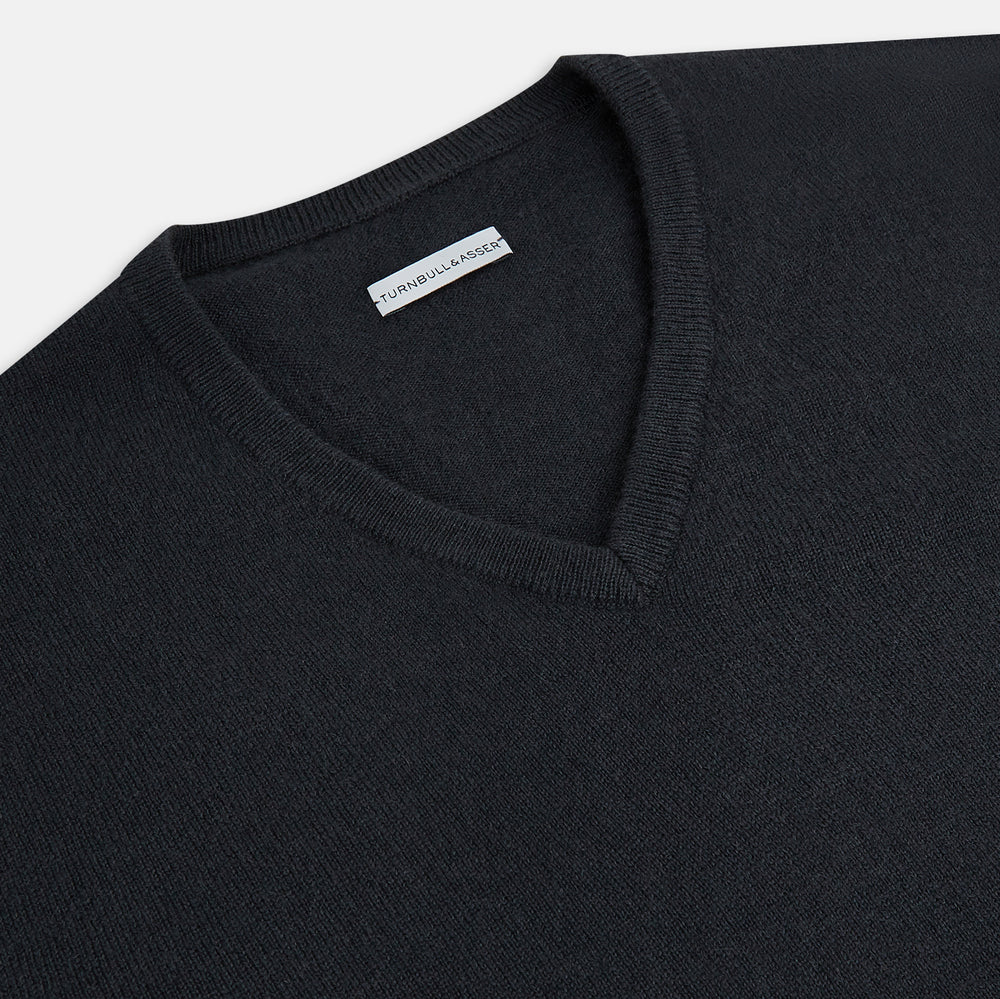 The Turnbull & Asser Dark Green Cashmere V-Neck Jumper features long sleeves, ribbed cuffs, and a ribbed waistband, showcased against a white background.
