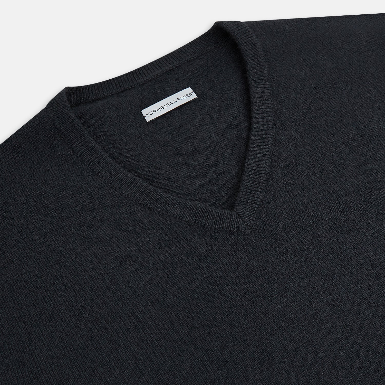 View 2 of product The Turnbull & Asser Dark Green Cashmere V-Neck Jumper features long sleeves, ribbed cuffs, and a ribbed waistband, showcased against a white background.