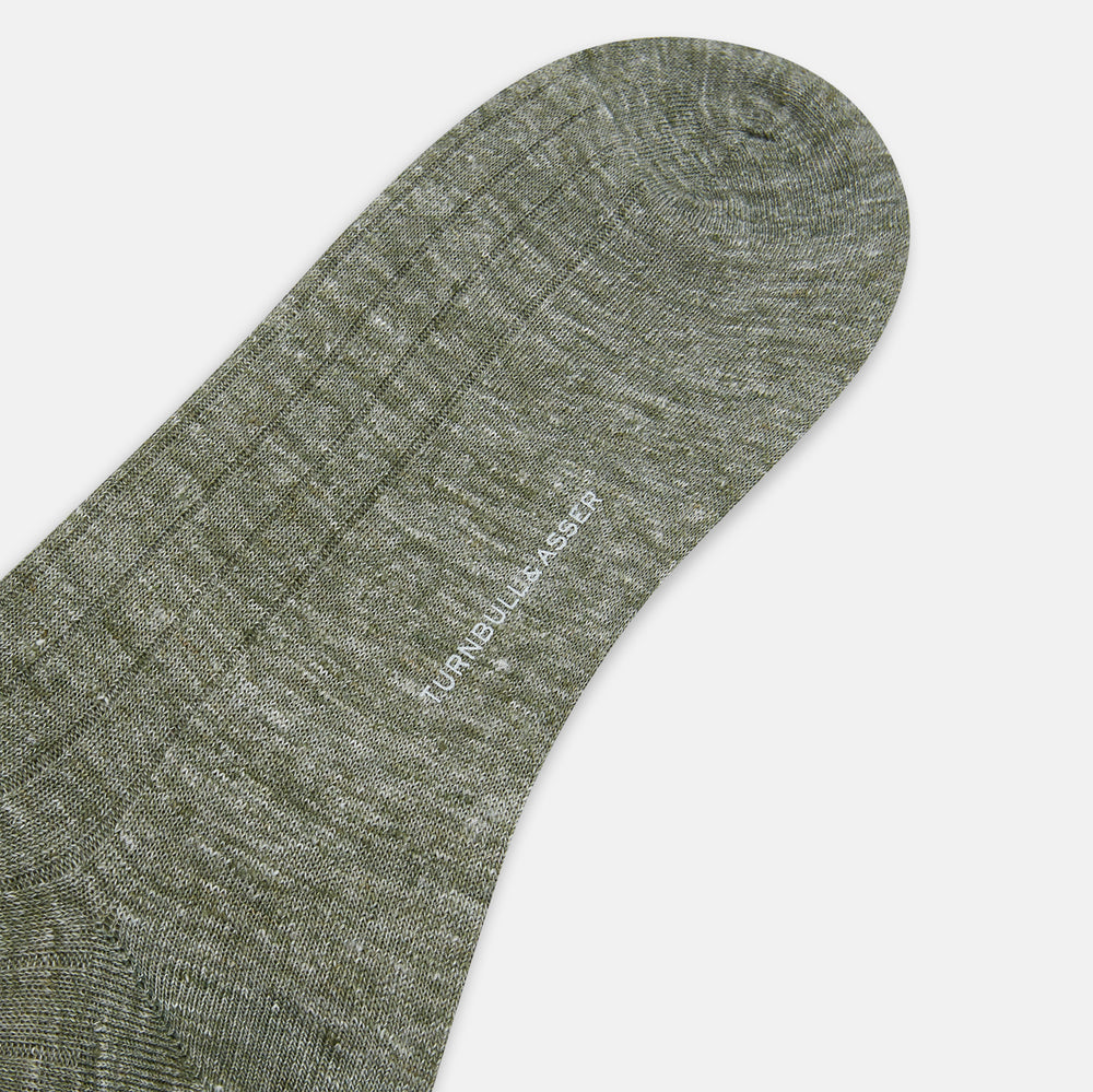 The Forest Green Linen Mid-Length Sock by Turnbull & Asser features a ribbed texture and is shown upright on a plain white background. Made from breathable linen, it offers comfort and style for everyday wear.