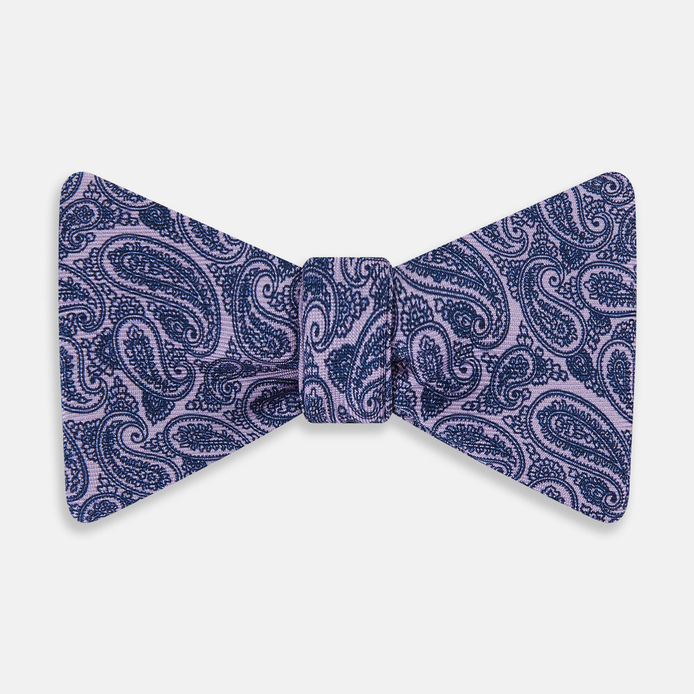 The Turnbull & Asser Lilac Paisley Silk Bow Tie features a refined dark blue pattern on lilac silk, shown on a plain white background—an elegant men's accessory for any occasion.