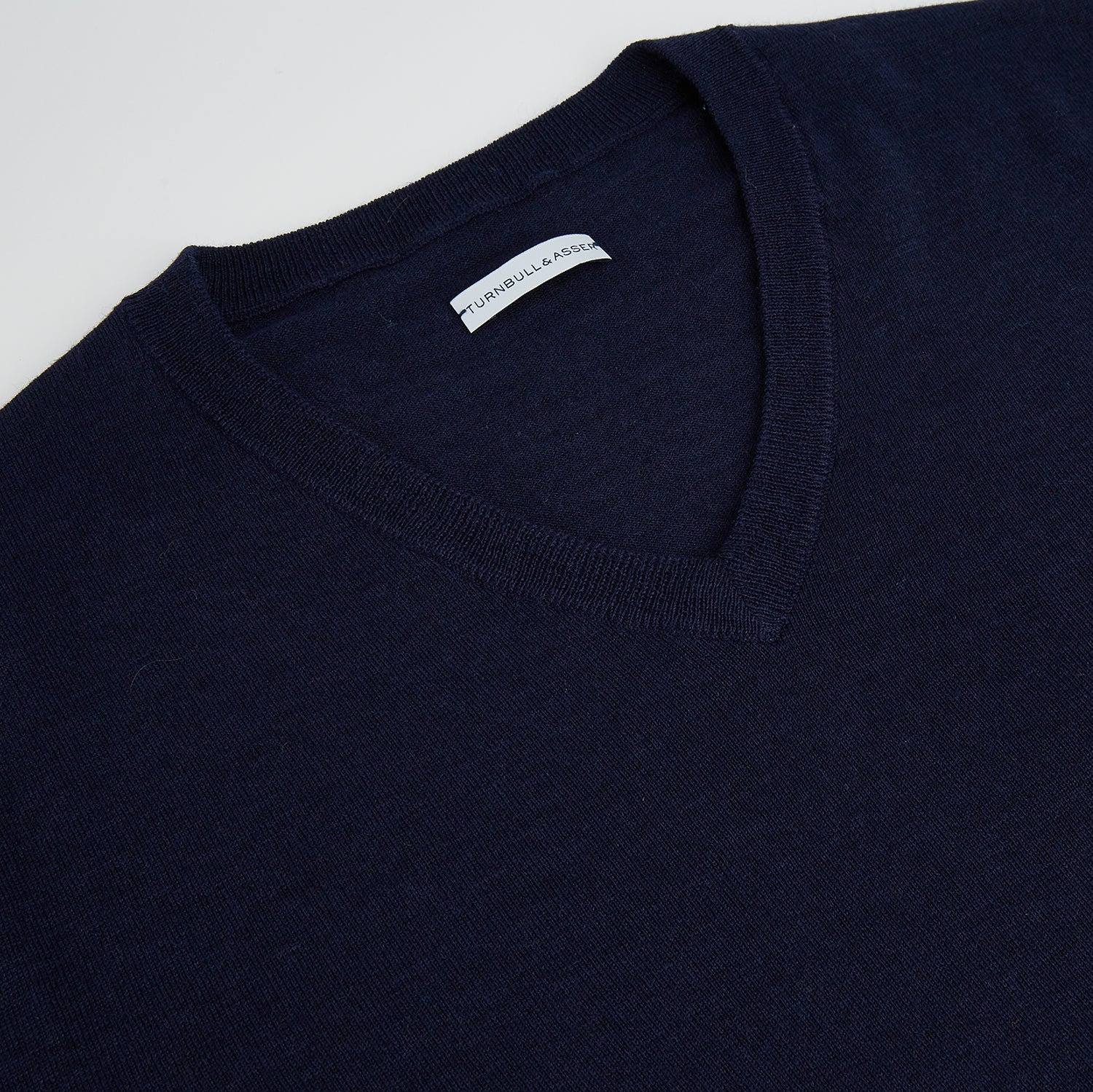 View 7 of product The Turnbull & Asser Navy Fine Merino V-Neck Jumper is displayed against a white background, featuring ribbed cuffs and hem for timeless style in a classic, plain long-sleeve design.