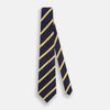 View 4 of product The Turnbull & Asser White and Navy Blazer Silk Tie, featuring diagonal yellow and white stripes, is rolled up neatly on a light gray background.