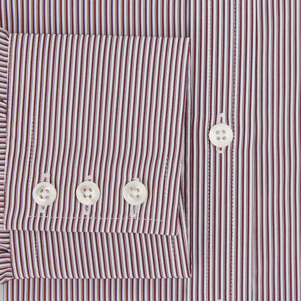 The Turnbull & Asser Burgundy Shadow Stripe Mayfair Shirt is a long-sleeved button-up with thin vertical burgundy stripes, classic collar, and buttoned cuffs, shown laid flat on a white background.