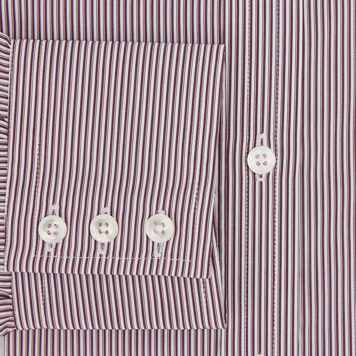 View 4 of product The Turnbull & Asser Burgundy Shadow Stripe Mayfair Shirt is a long-sleeved button-up with thin vertical burgundy stripes, classic collar, and buttoned cuffs, shown laid flat on a white background.