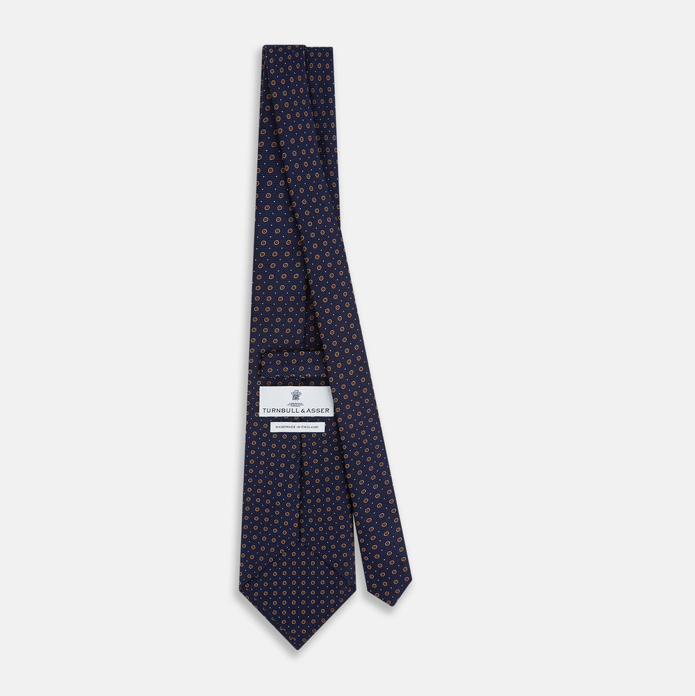 The Turnbull & Asser Navy and Grey Circle Silk Tie, featuring a refined pattern of evenly spaced circles, is elegantly displayed rolled up on a white background—an excellent option for modern office wear.