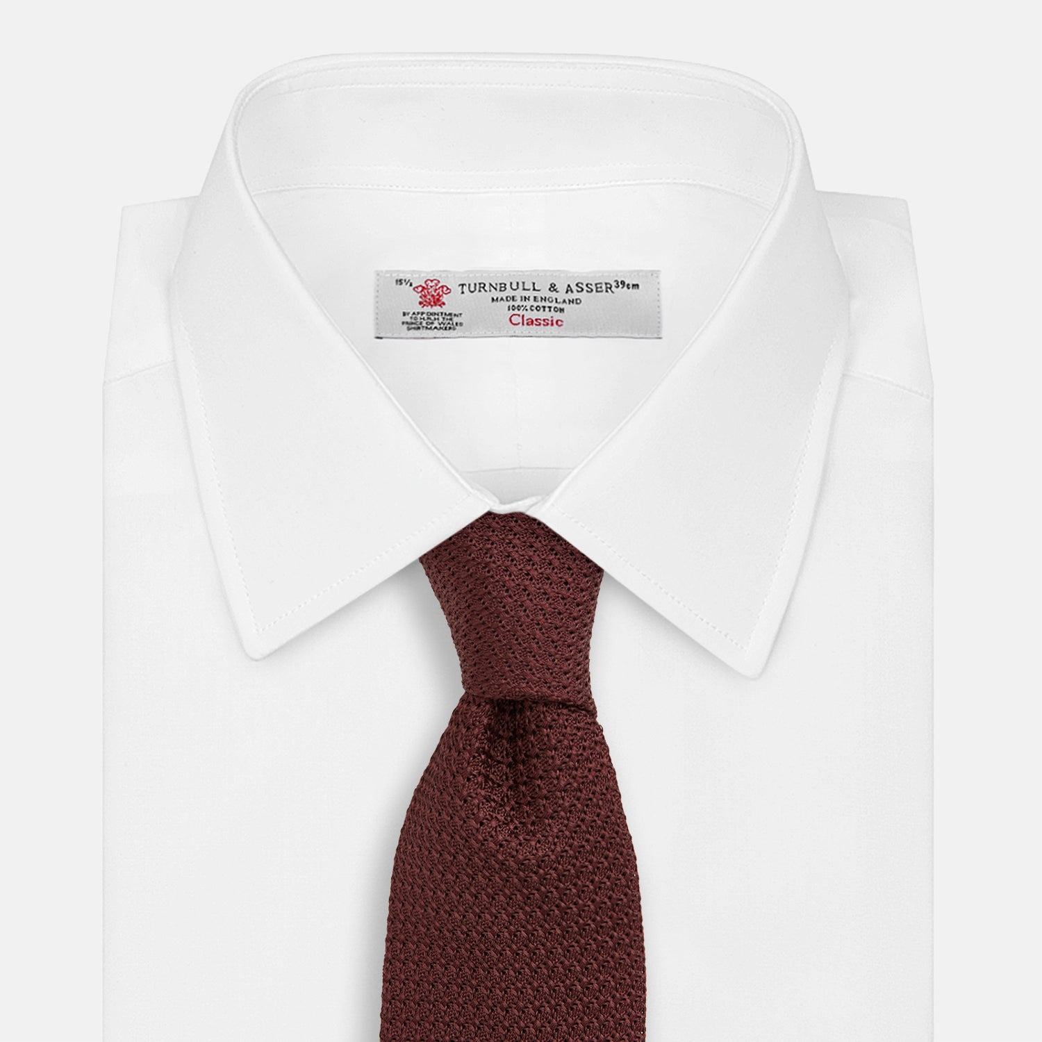 View 2 of product The Turnbull & Asser Ruby Red Knitted Tie, shown rolled-up against a white background, is a textured silk accessory that adds versatile sophistication to any gentleman's wardrobe.