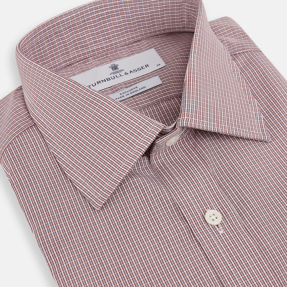 The Turnbull & Asser Burgundy Micro Shadow Check Mayfair Shirt features long sleeves, a classic collar, and white buttons. In light red and white shades, this button-up is perfect for formal wear and is shown laid flat against a white background.