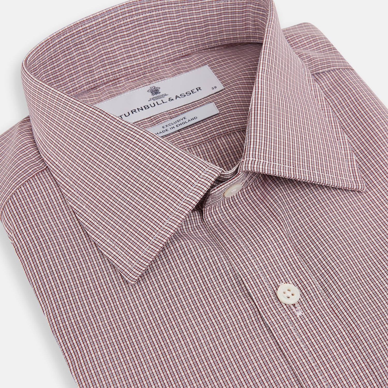 View 2 of product The Turnbull & Asser Burgundy Micro Shadow Check Mayfair Shirt features long sleeves, a classic collar, and white buttons. In light red and white shades, this button-up is perfect for formal wear and is shown laid flat against a white background.