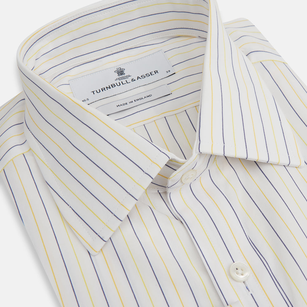 The Turnbull & Asser Yellow Double Pinstripe Mayfair Shirt, a long-sleeved, button-up with thin blue and yellow stripes on white, classic T&A collar, and buttoned cuffs, is laid flat on a white surface.