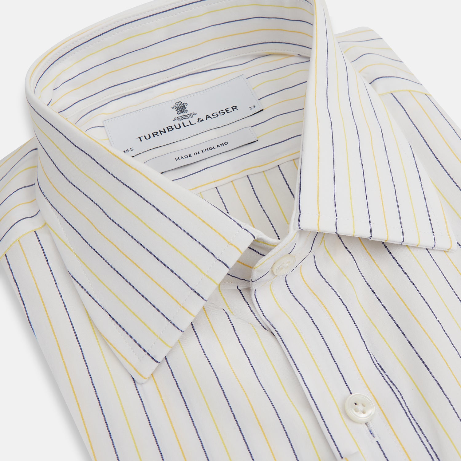 View 2 of product The Turnbull & Asser Yellow Double Pinstripe Mayfair Shirt, a long-sleeved, button-up with thin blue and yellow stripes on white, classic T&A collar, and buttoned cuffs, is laid flat on a white surface.