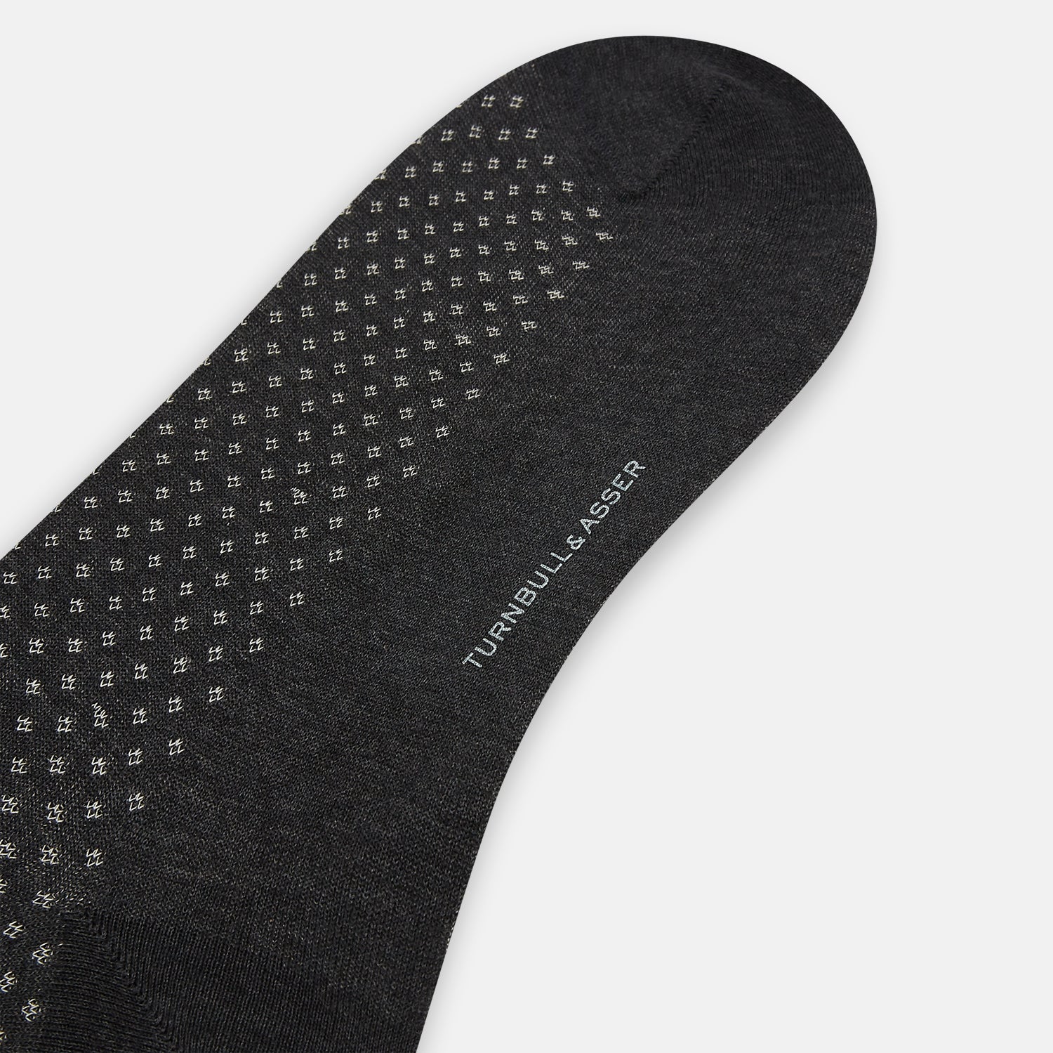 View 3 of product Turnbull & Asser Grey Motif Mid-Length Sock, crafted from Egyptian cotton, features a fine white geometric dot pattern on grey with a solid black cuff, heel, and toe for classic style. Displayed on a white background.