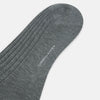 View 4 of product The Ash Mid-Length Sock by Turnbull & Asser, shown upright on a plain white background, is a single dark gray ribbed knee-high made from mercerised Egyptian cotton.