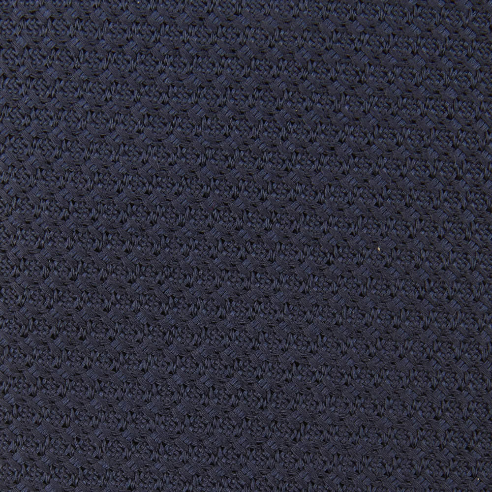 The Turnbull & Asser Plain Woven Grenadine Silk Tie in navy, with a textured finish, is rolled and displayed on a white background—a refined essential for any wardrobe.