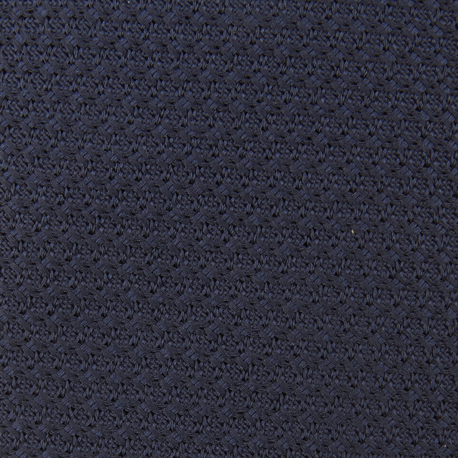 View 4 of product The Turnbull & Asser Plain Woven Grenadine Silk Tie in navy, with a textured finish, is rolled and displayed on a white background—a refined essential for any wardrobe.