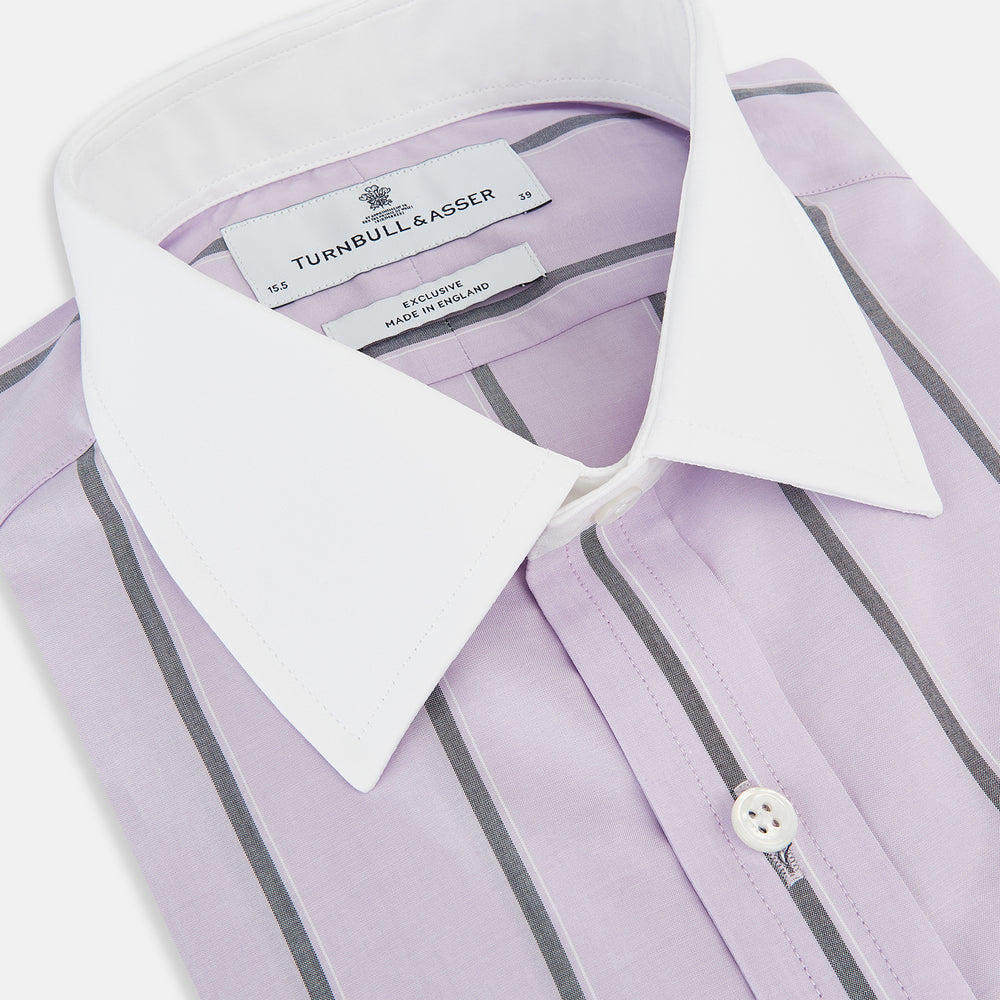The Turnbull & Asser Lilac Track Stripe Shirt with Contrast T&A Collar and Cuffs features vertical black stripes, a white pointed collar, and white cuffs, shown flat against a white background.