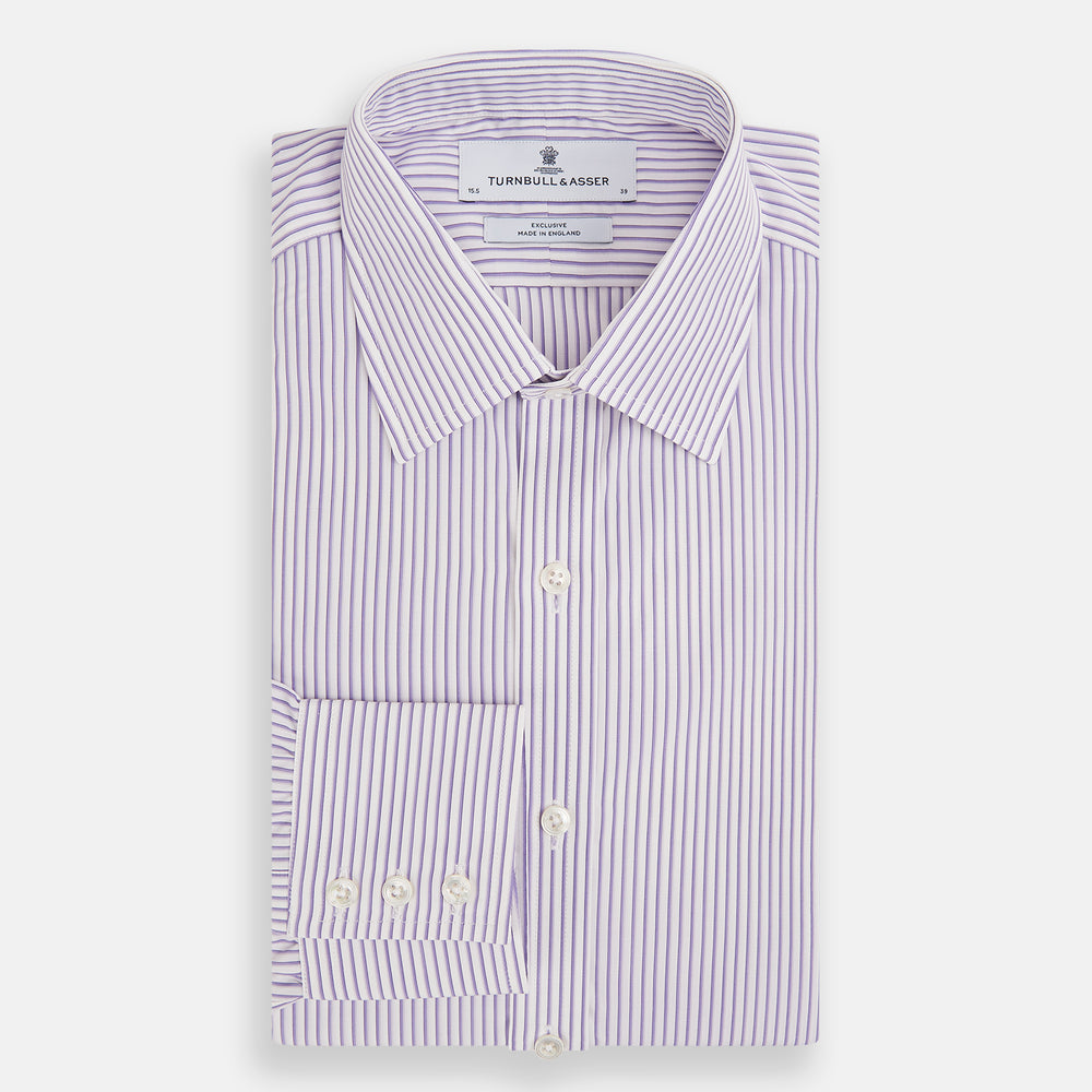 The Turnbull & Asser Purple Shadow Stripe Mayfair Shirt features a long-sleeve button-up design with thin vertical blue and white stripes, a T&A collar, and buttoned cuffs, shown on a plain white background.