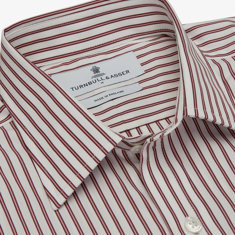 The Turnbull & Asser Burgundy Stripe Weekend Fit Shirt features a Derby collar, 1-button cuffs, and vertical burgundy and white stripes, shown laid flat on a plain light background.