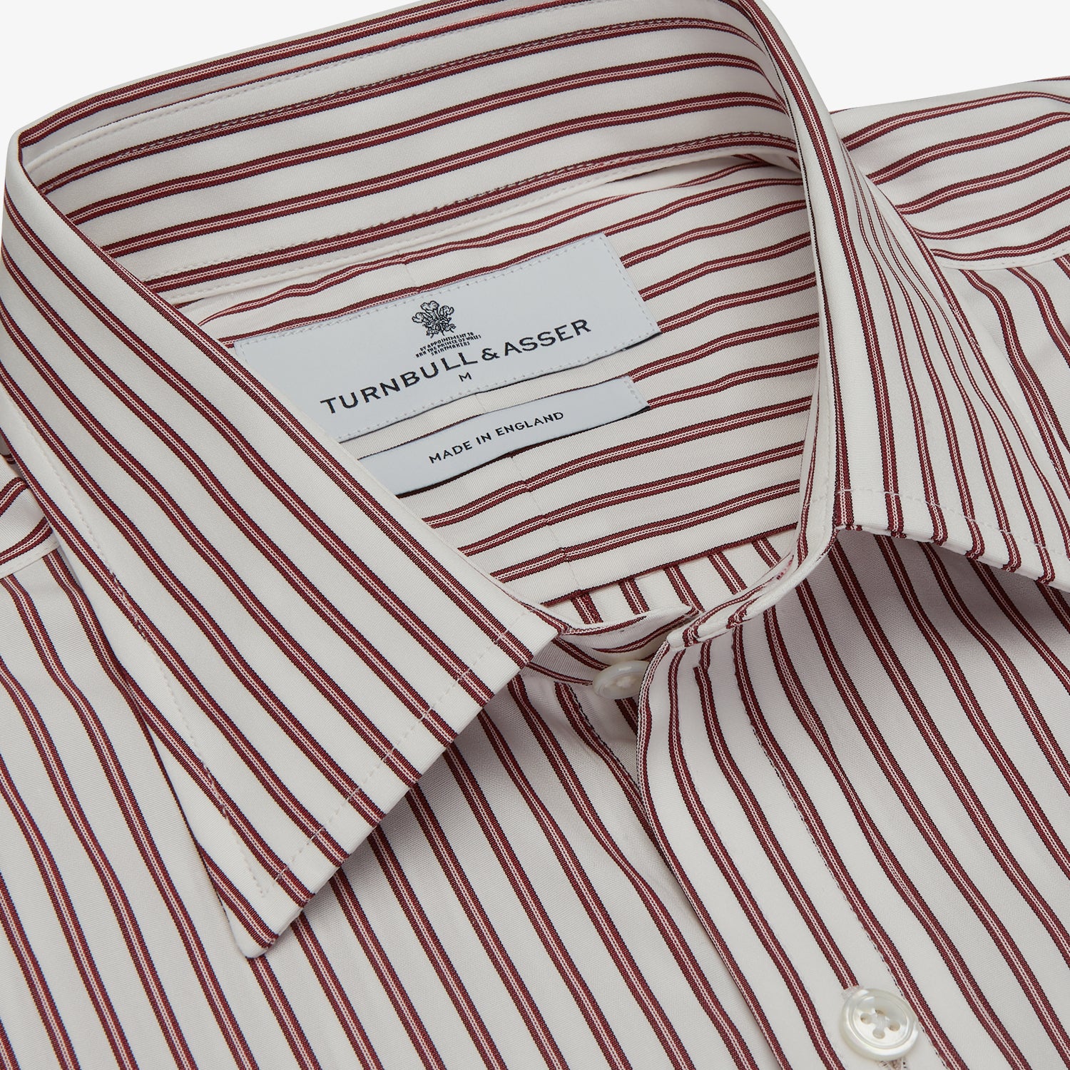 View 4 of product The Turnbull & Asser Burgundy Stripe Weekend Fit Shirt features a Derby collar, 1-button cuffs, and vertical burgundy and white stripes, shown laid flat on a plain light background.