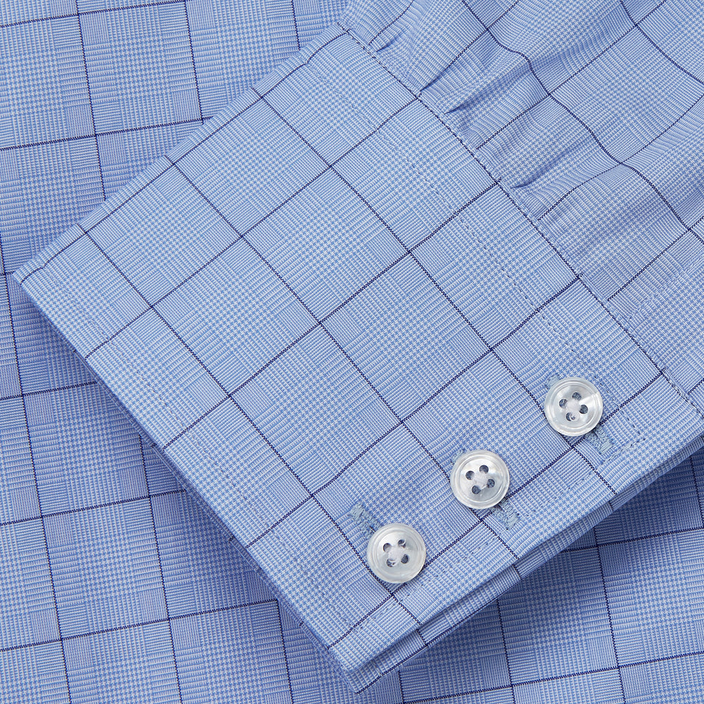 The Blue Prince of Wales Check Mayfair Shirt by Turnbull & Asser is a light blue formal long-sleeve shirt with a subtle check pattern, button-down front, and buttoned cuffs, shown laid flat on a white background.