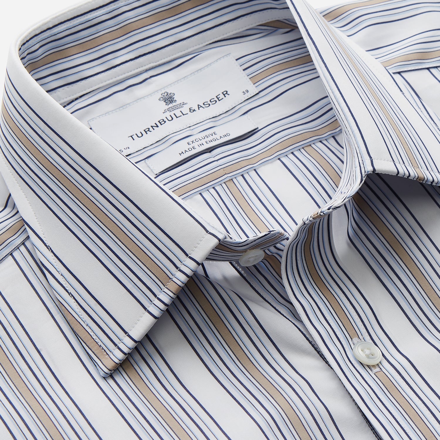 View 2 of product The Turnbull & Asser Sand Multi Stripe Regular Fit Shirt features a T&A collar, 3 button cuffs, and vertical blue, white, and light brown stripes. The shirt is shown neatly laid flat on a white background.