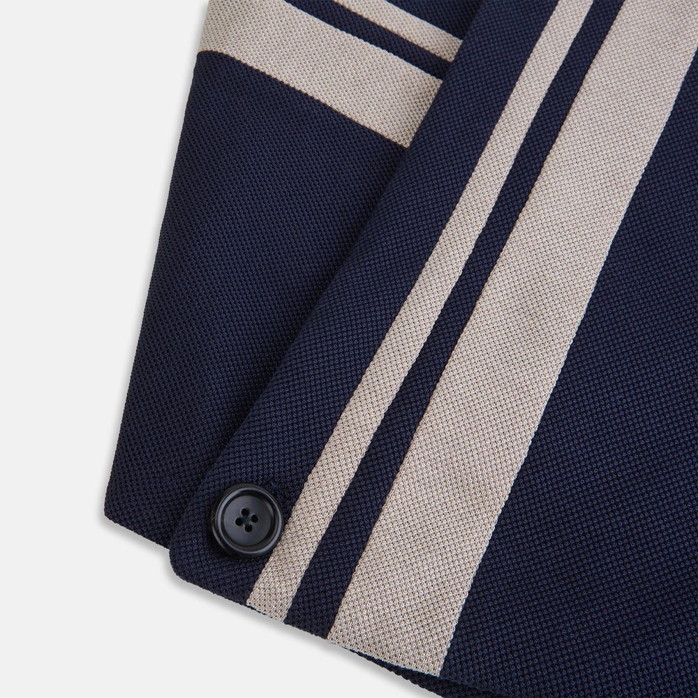 The Navy and Sand Stripe Neck Warmer by Turnbull & Asser features two beige diagonal stripes and a black button, draped in a V shape on a white background—an elegant formal accessory for any occasion.