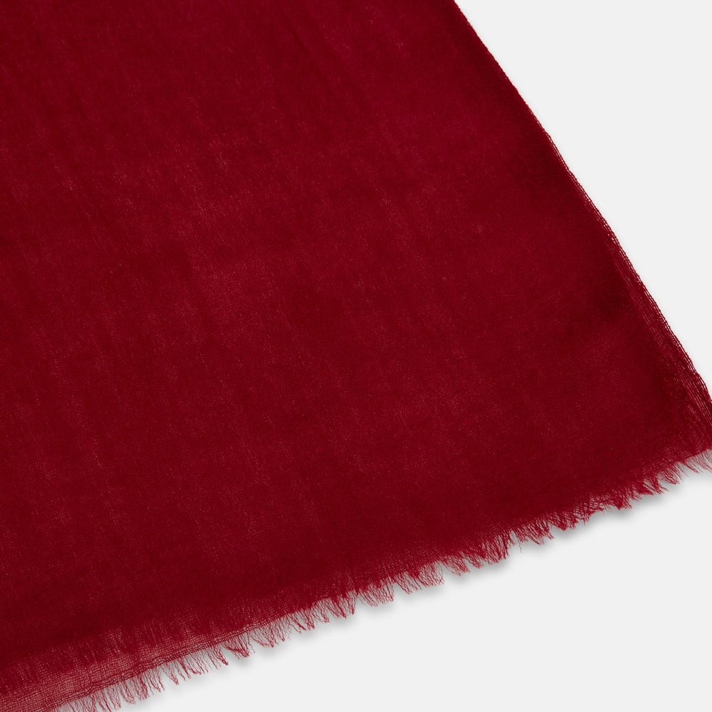The Burgundy Cashmere Scarf by Turnbull & Asser features a soft texture, deep red hue, and lightly frayed edges, loosely knotted and displayed on a plain white background—an elegant luxury accessory.