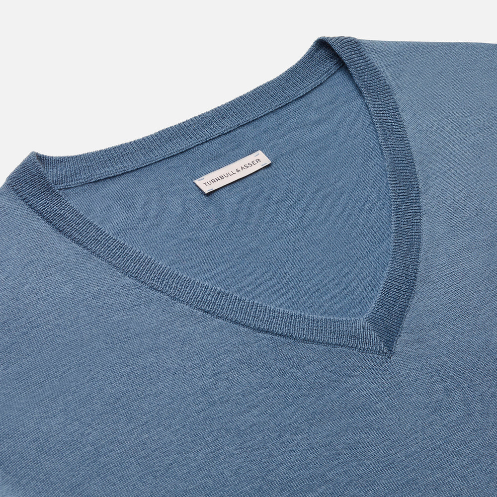 The Turnbull & Asser Pale Blue Fine Merino V-Neck Jumper features long sleeves, ribbed cuffs, and a straight hem. Shown against a white background, this classic knitwear combines comfort and style.