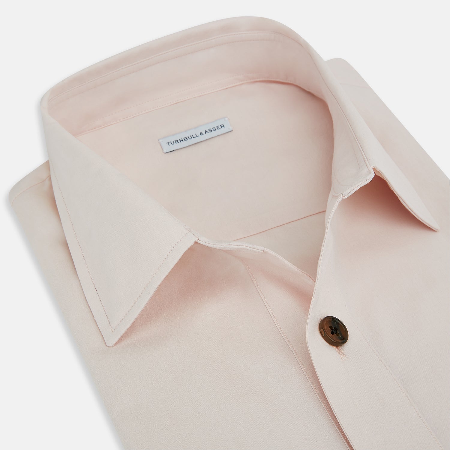 View 2 of product The Turnbull & Asser Pale Pink Hyde Overshirt is a long-sleeve, sanforised cotton button-up with a left chest pocket and dark buttons, shown laid flat on a white background.