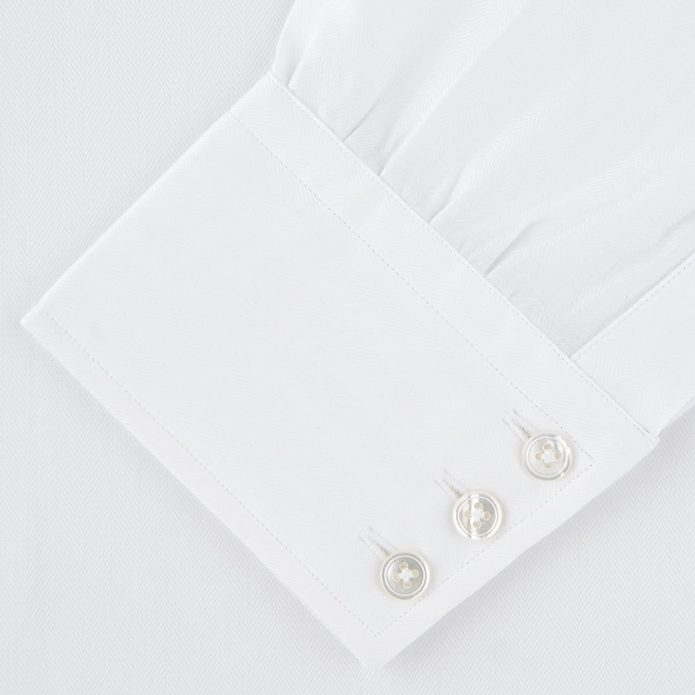 The Turnbull & Asser White Self-On-Self Herringbone Sea Island Quality Cotton Shirt features a T&A collar, 3-button cuffs, and luxurious Egyptian cotton, displayed neatly folded against a light gray background.