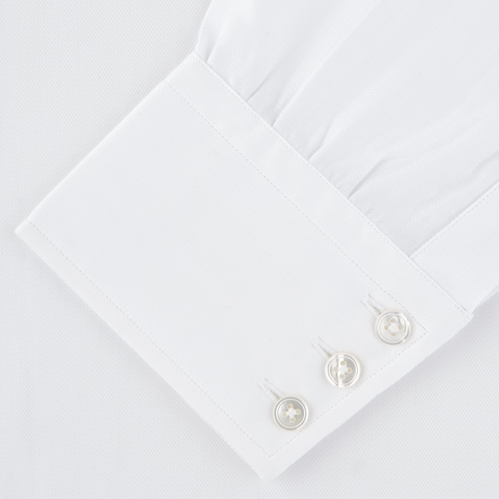 View 2 of product The Turnbull & Asser White Self-On-Self Herringbone Sea Island Quality Cotton Shirt features a T&A collar, 3-button cuffs, and luxurious Egyptian cotton, displayed neatly folded against a light gray background.
