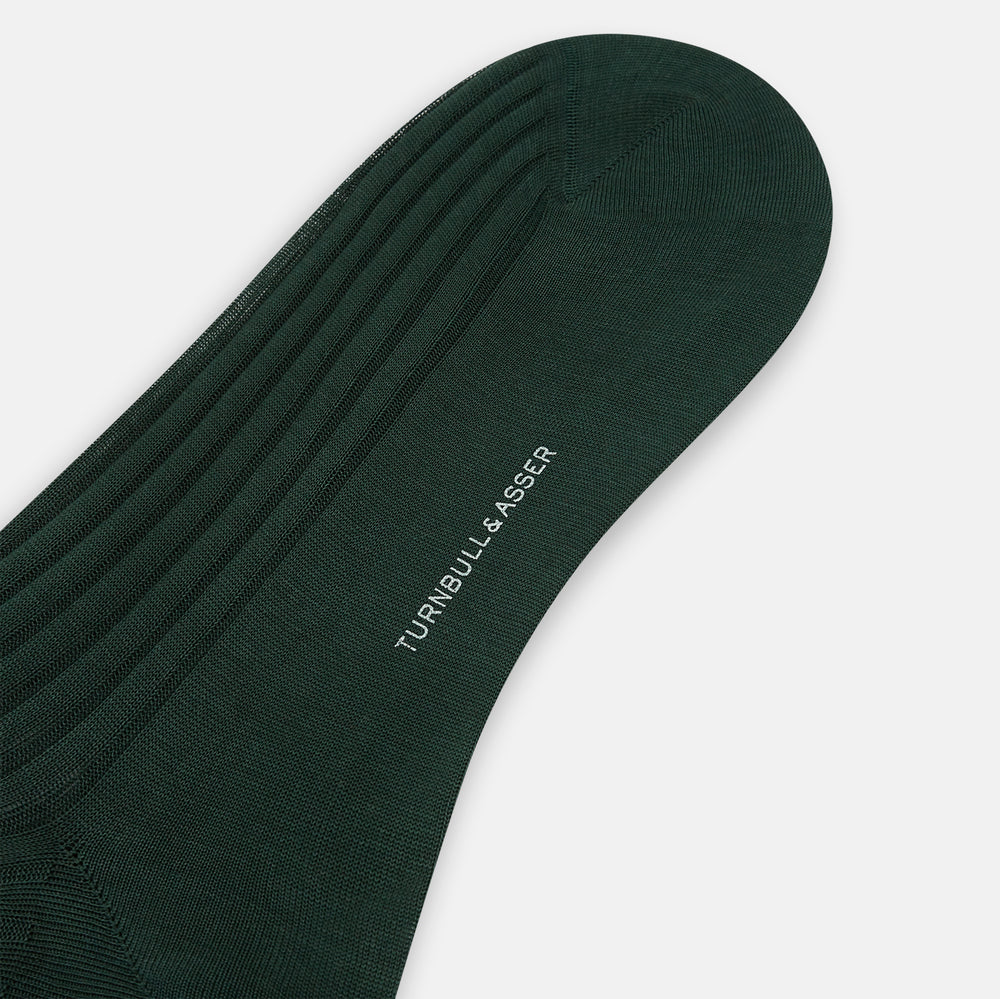 Turnbull & Asser's Olive Mid-Length Socks, crafted from mercerised Egyptian cotton in dark green with ribbed detailing, are displayed against a plain white background, showcasing refined comfort and enduring style.