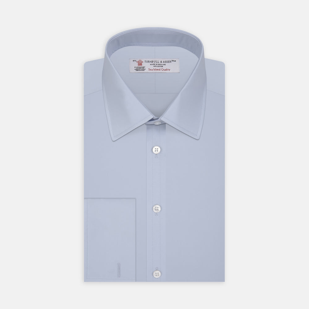 The Turnbull & Asser Light Blue Sea Island Quality Cotton Shirt features a T&A collar, double cuffs, white buttons, and a quality label inside the collar. Displayed on a plain white background.