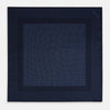 View 4 of product The Turnbull & Asser Midnight Blue Dot Silk Pocket Square features a neatly folded, handmade design with small light blue polka dots and a plain border.