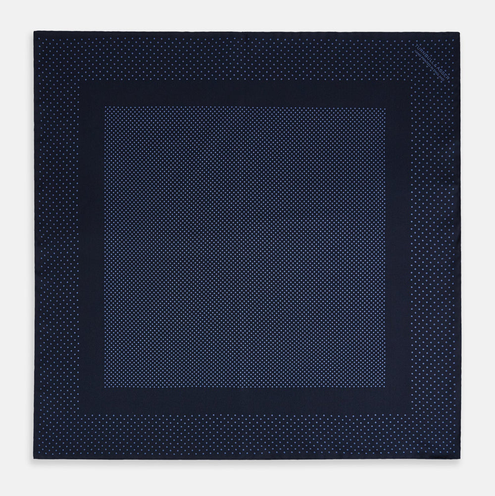 The Turnbull & Asser Midnight Blue Dot Silk Pocket Square features a neatly folded, handmade design with small light blue polka dots and a plain border.
